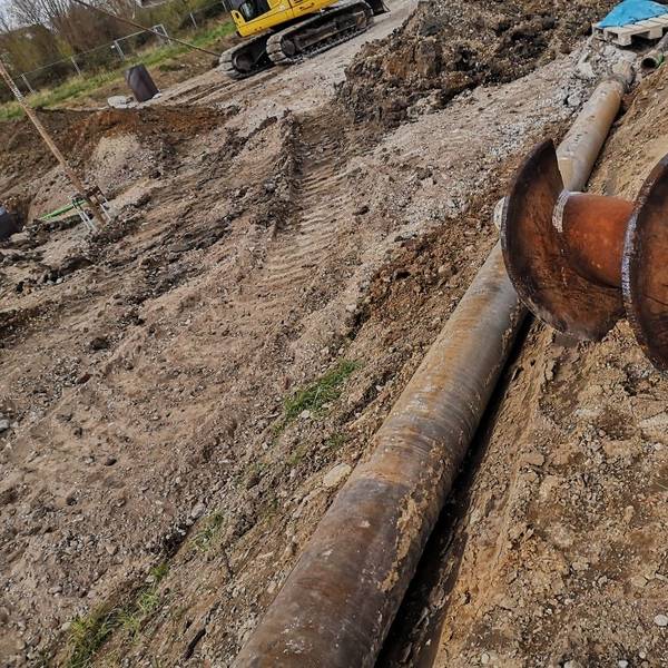 Ein großer Bohrer, umgeben von Erde, auf einer Baustelle.