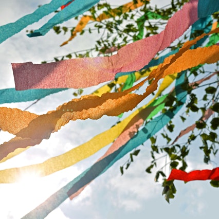 Bunte Bänder an einem Maibaum flattern im Wind.