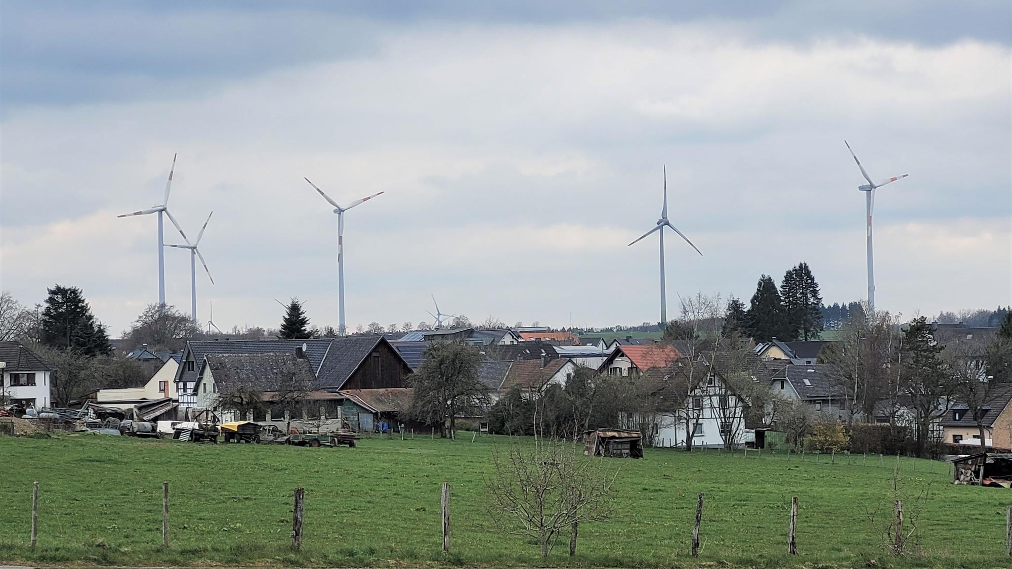 Blick auf Schöneseiffen mit mehreren Windrädern im Hintergrund.