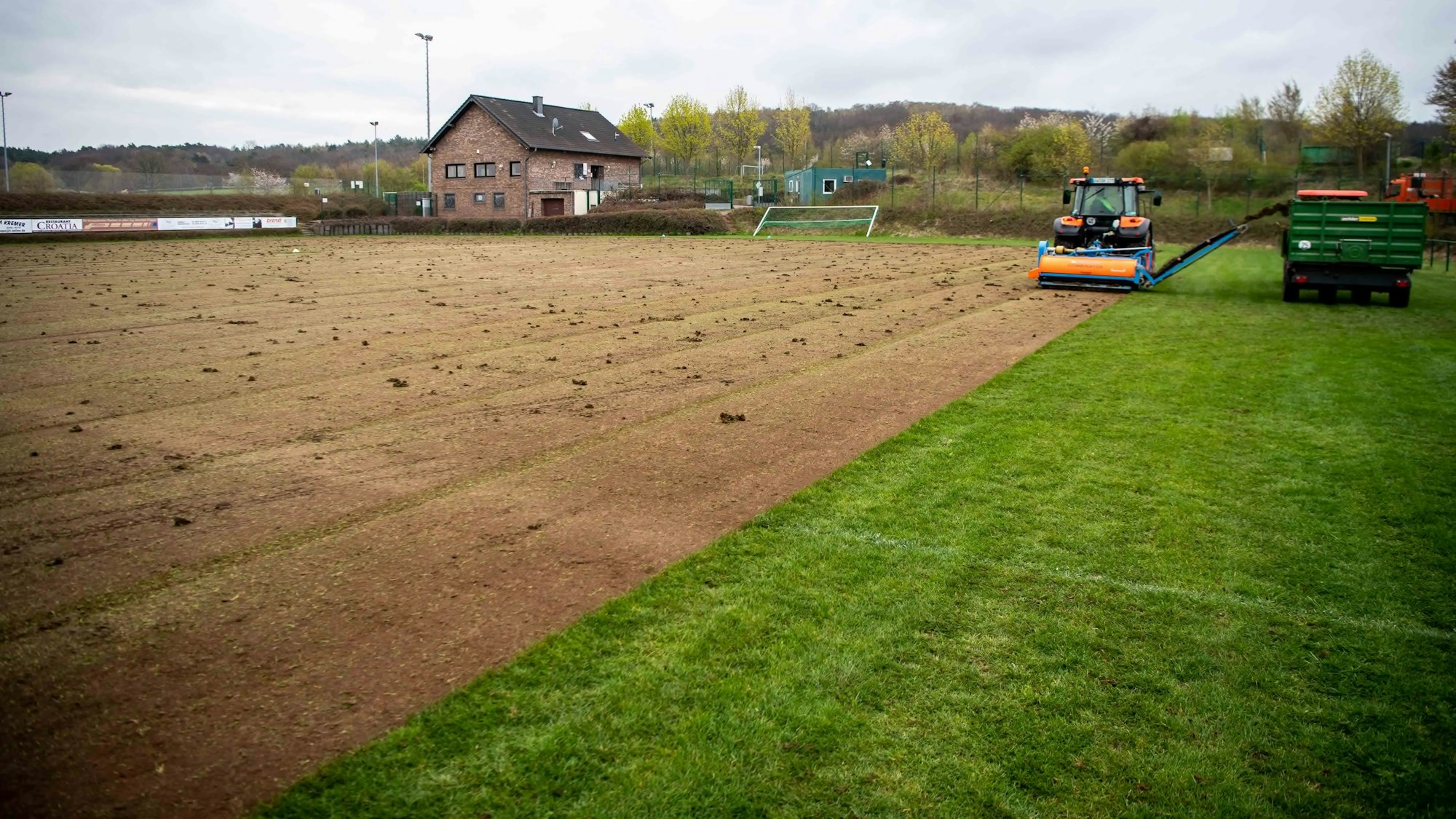 Mit schwerem Gerät wird der Kommerner Rasenplatz abgeschält. Zu sehen sind noch Rest-Rasenflächen und die braune Fläche ohne Rasen.