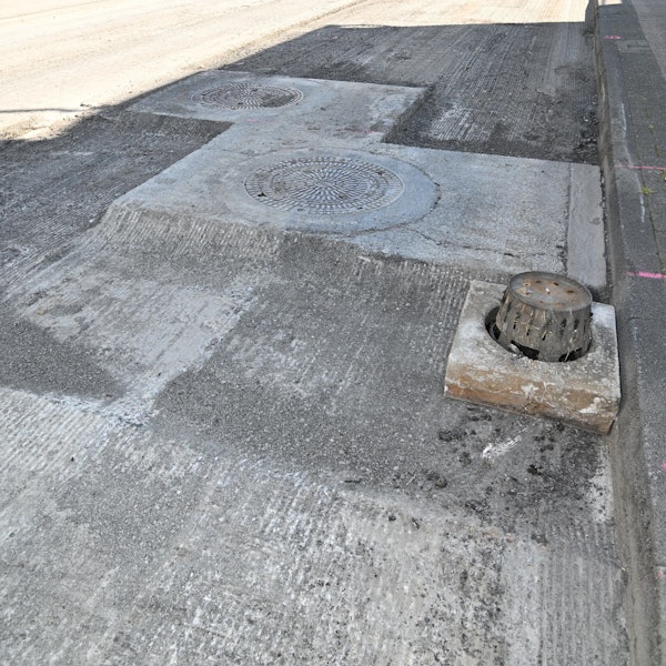 Eine gesperrte Straße ist abgefräst worden, die Kanaldeckel stehen über dem Straßenniveau.