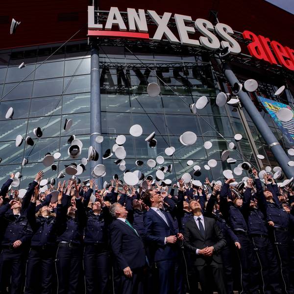 Polizeianwärter werfen ihre Mützen vor der Lanxess Arena in die Luft.