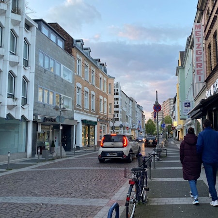 Das Foto zeigt die Kölnstraße in Brühl. Sie wird von mehreren Autos befahren, auf dem Bürgersteig gehen zwei Passanten.