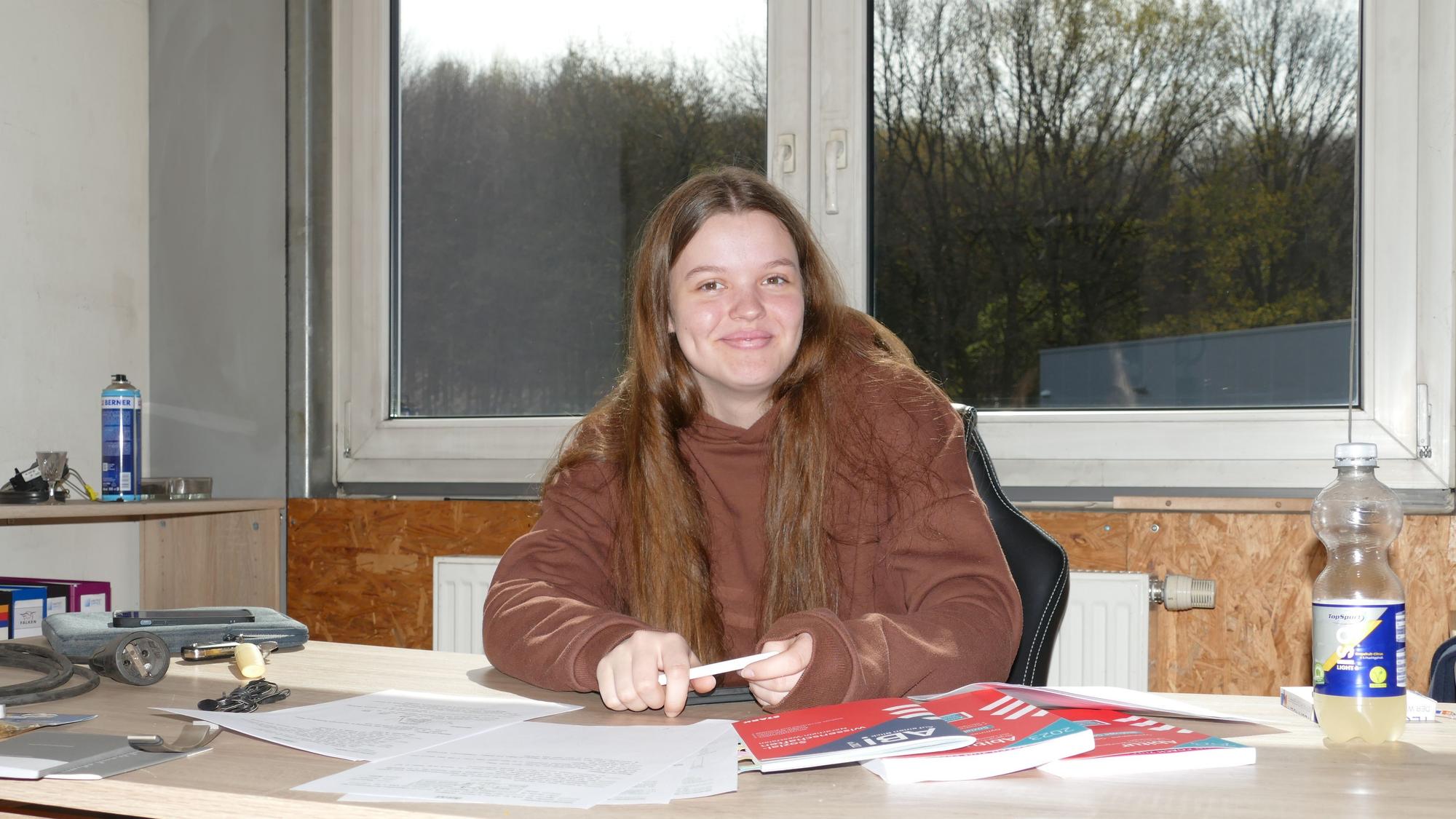 Eine junge Frau sitzt am Schreibtisch.