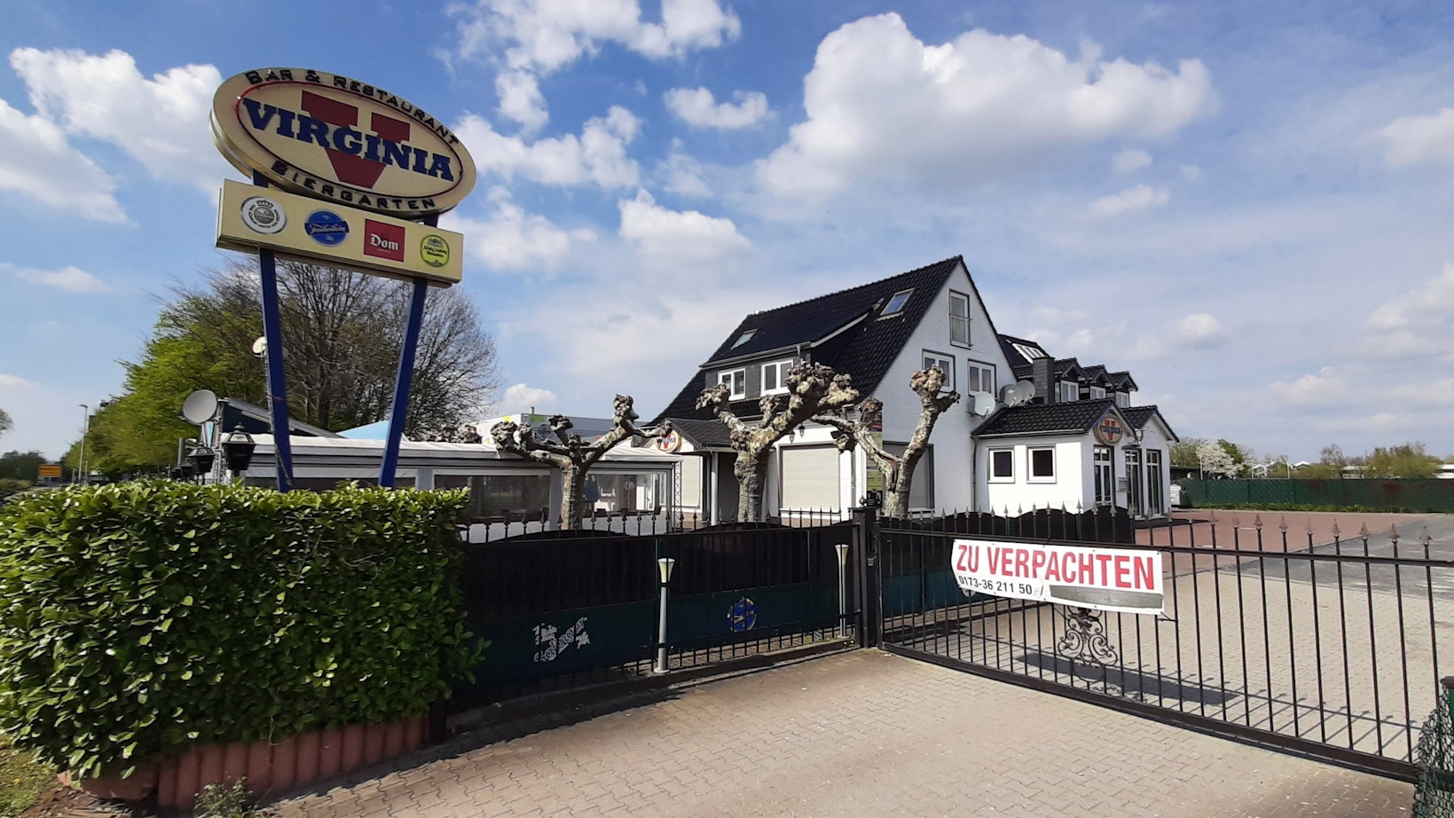 Das Gebäude des Virginia American Bar Restaurant befindet sich hinter einem Zaun und einer Hecke. „Zu verpachten" ist auf einem Schild am Eingangstor zu lesen.