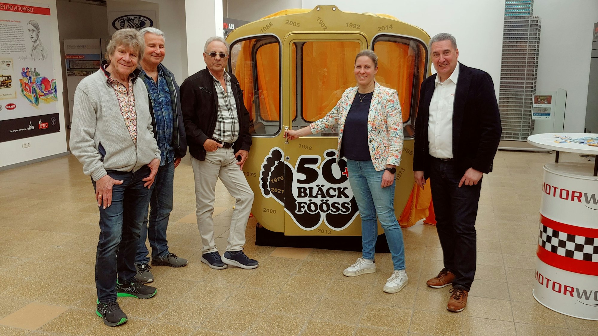 Fünf Personen vor einer gelben Gondel.