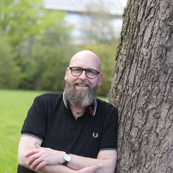 Portrait von Marc Franke. Er lehnt in einem Düsseldorfer Park an einem Baum.