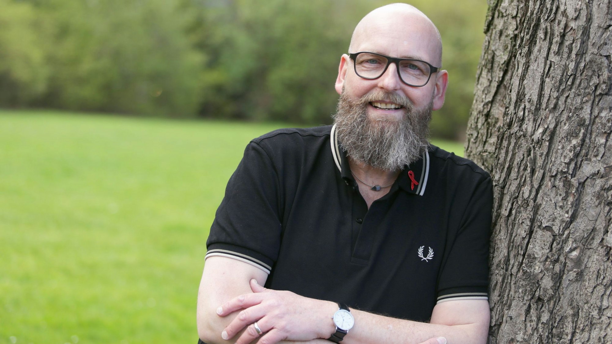 Portrait von Marc Franke. Er lehnt in einem Düsseldorfer Park an einem Baum.