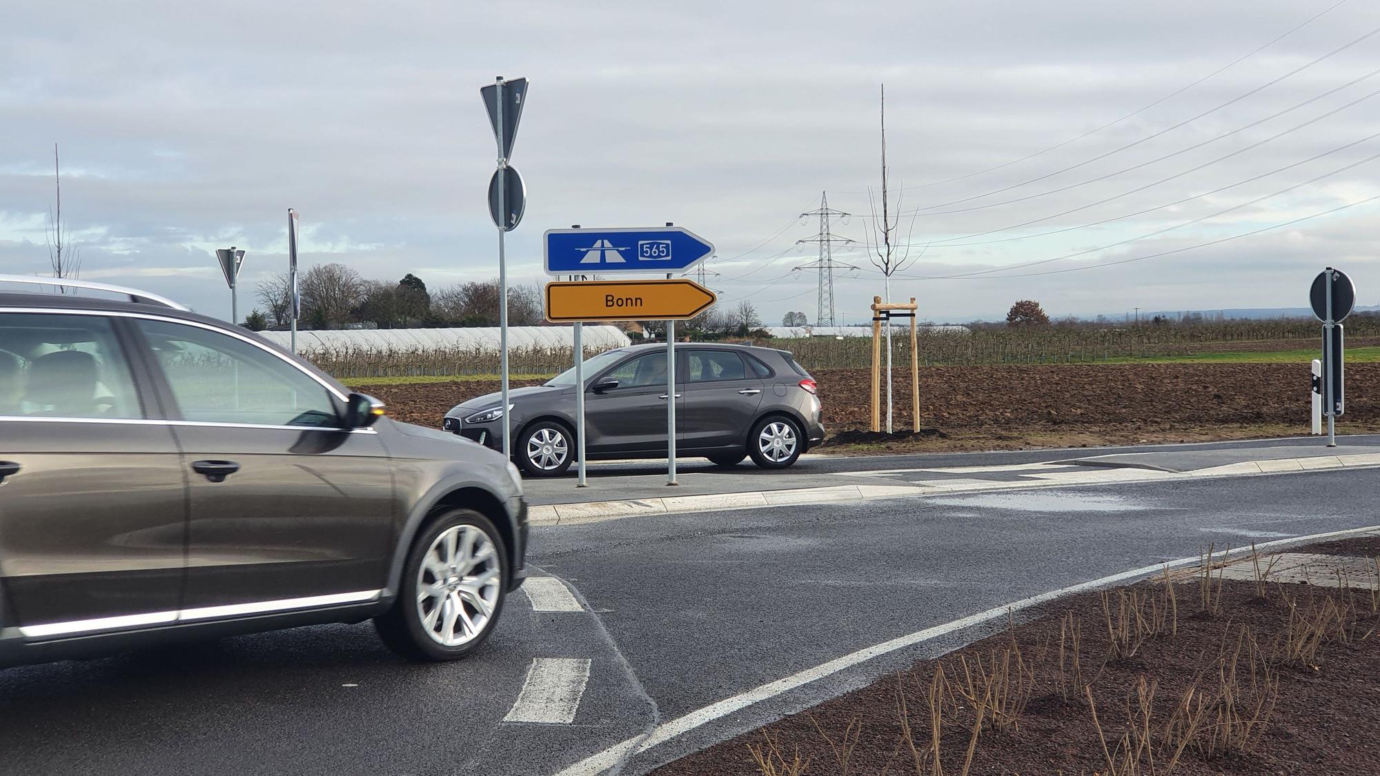 Zwei Autos an einem Abbiegeschild.
