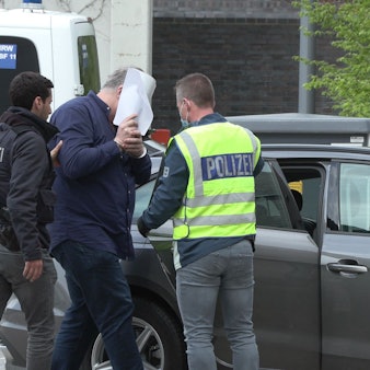 Ein Mann wird von zwei Beamten festgenommen.