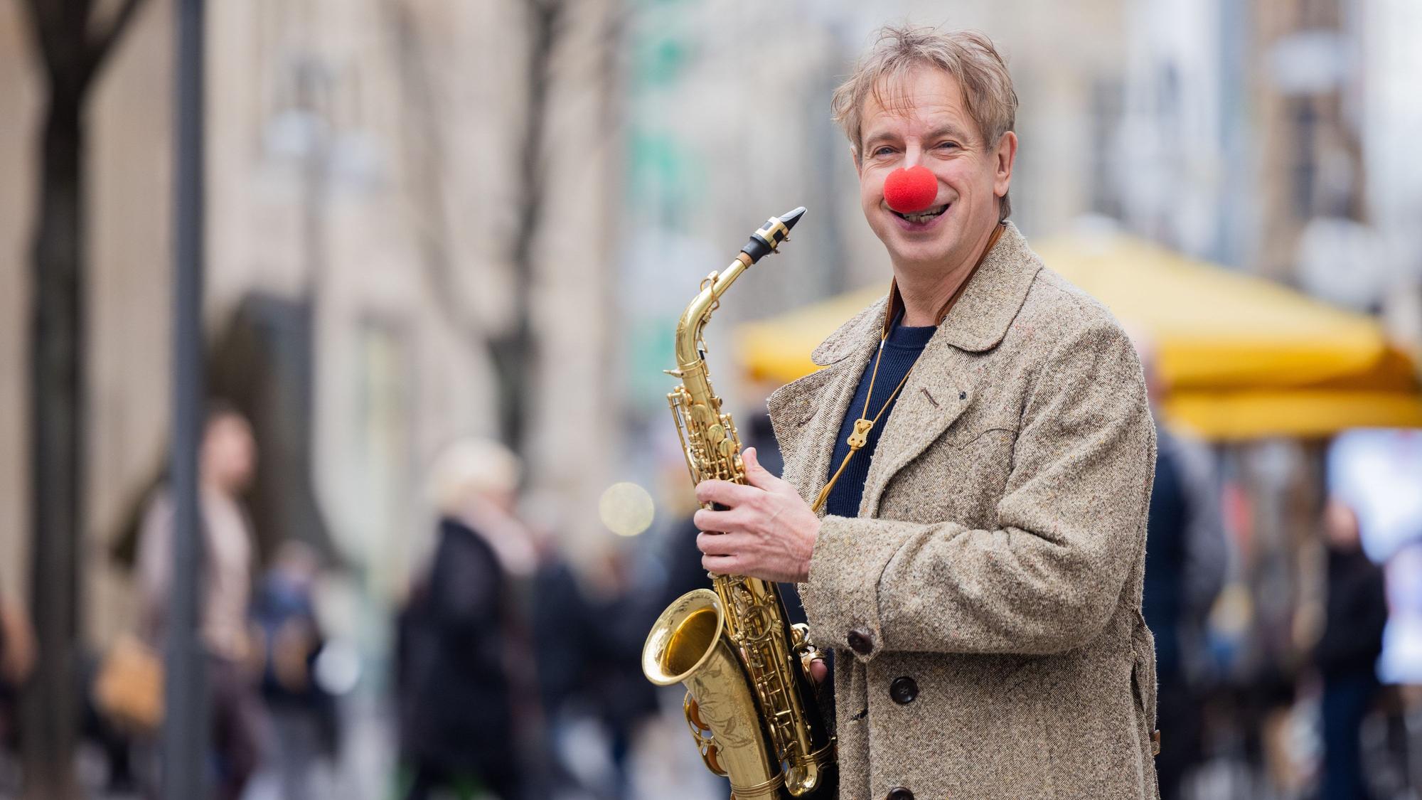 Ingolf Lück, Schauspieler, Moderator, Komiker, steht mit seinem Saxofon in der Innenstadt Köln.