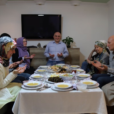 An einem reich gedeckten Tisch beten die Freunde gemeinsam vor dem Fastenbrechen.