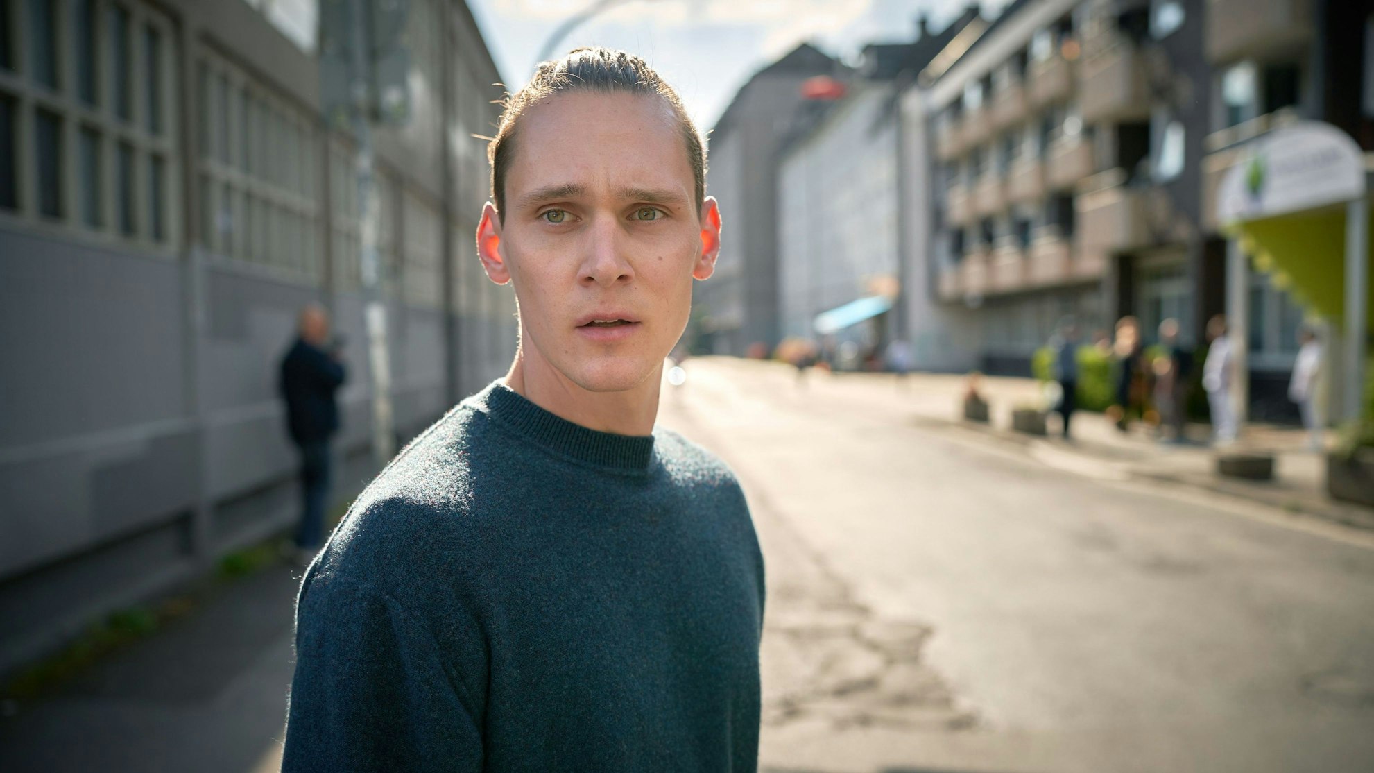 Jan Pawlak schaut bestürzt in Richtung der Kamera. Er steht an einer Straße, der Hintergrund ist verschwommen.