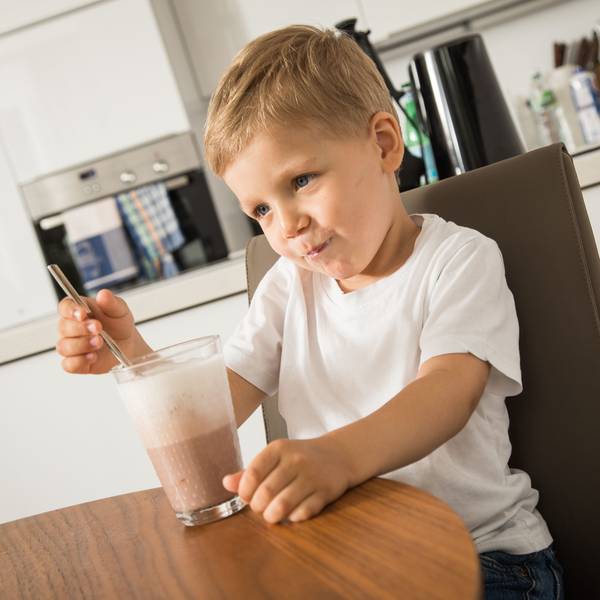 Kleiner Junge mit Kakaoglas am Tisch