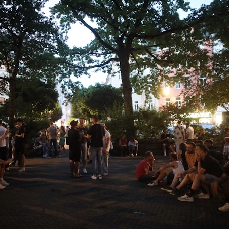 Eine warme Nacht am Brüsseler Platz. Menschen genießen den Frühsommer und verabreden sich.