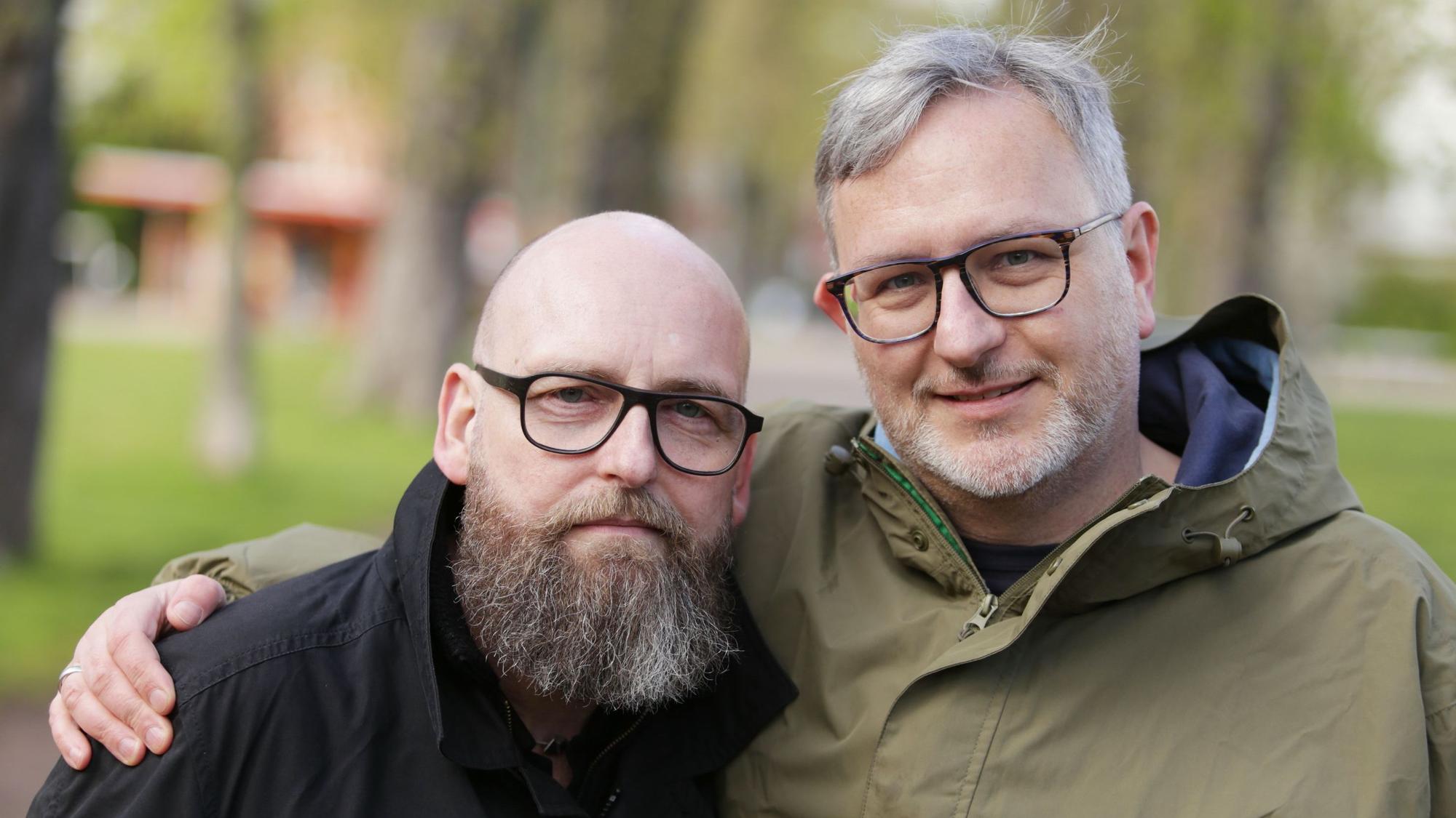 Franke und Sträter stehen in einem Park in Düsseldorf. Sträter hat den Arm um Franke gelegt.