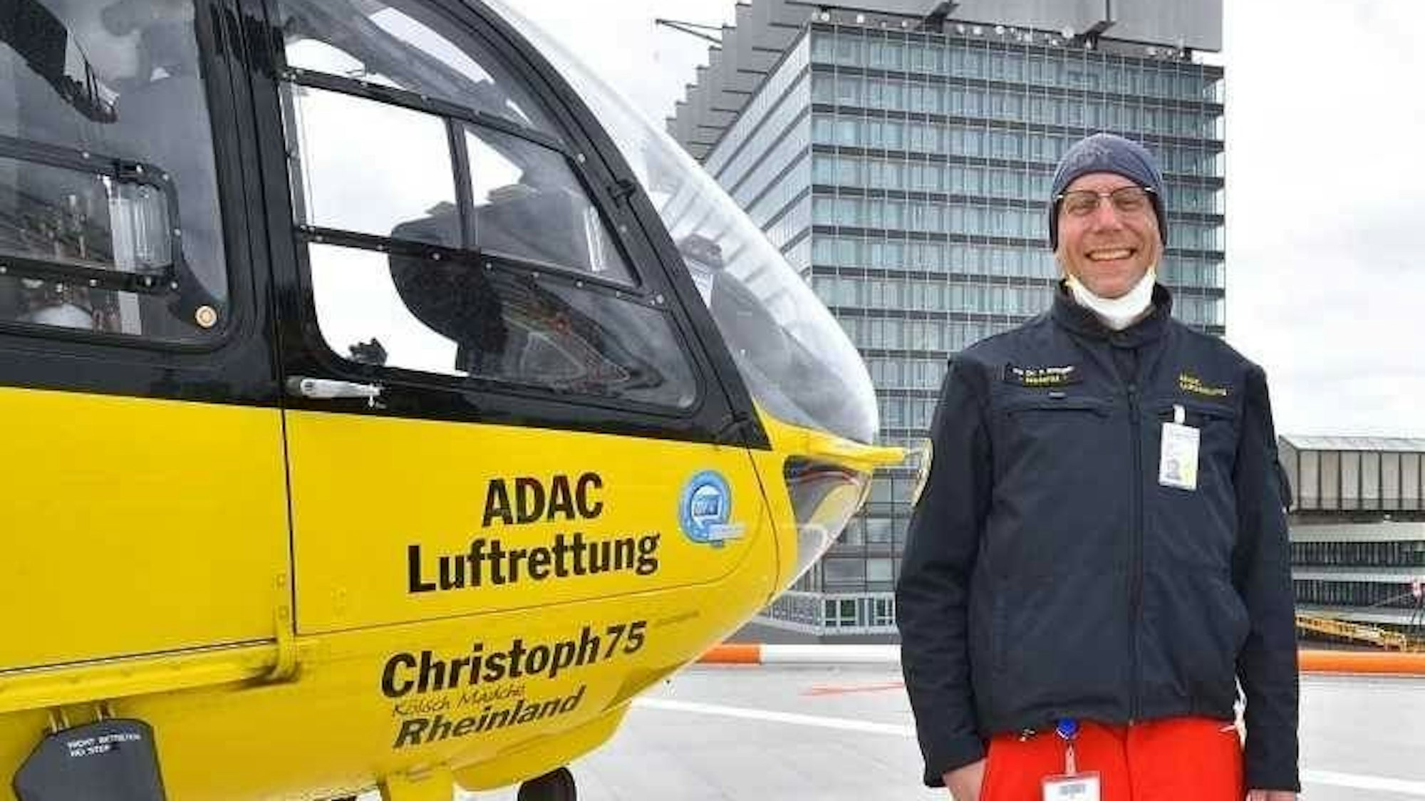 PD Dr. Eifinger lacht in die Kamera. Neben ihm ist die Spitze des ITH zu sehen. Die Aufschrift darauf lautet: „ADAC Luftrettung, Christoph 75 Rheinland, Kölsch Mädche“.