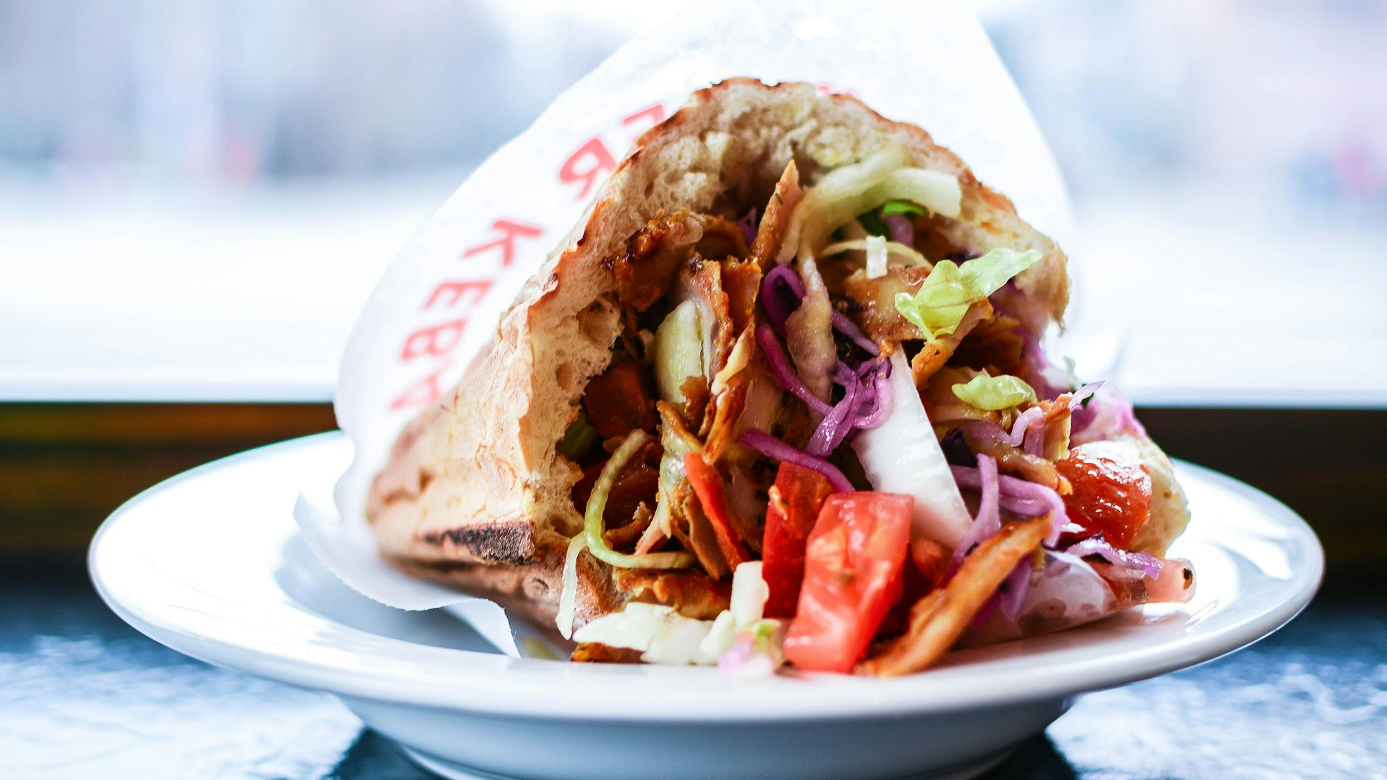 Eine Dönertasche liegt auf einem Teller.