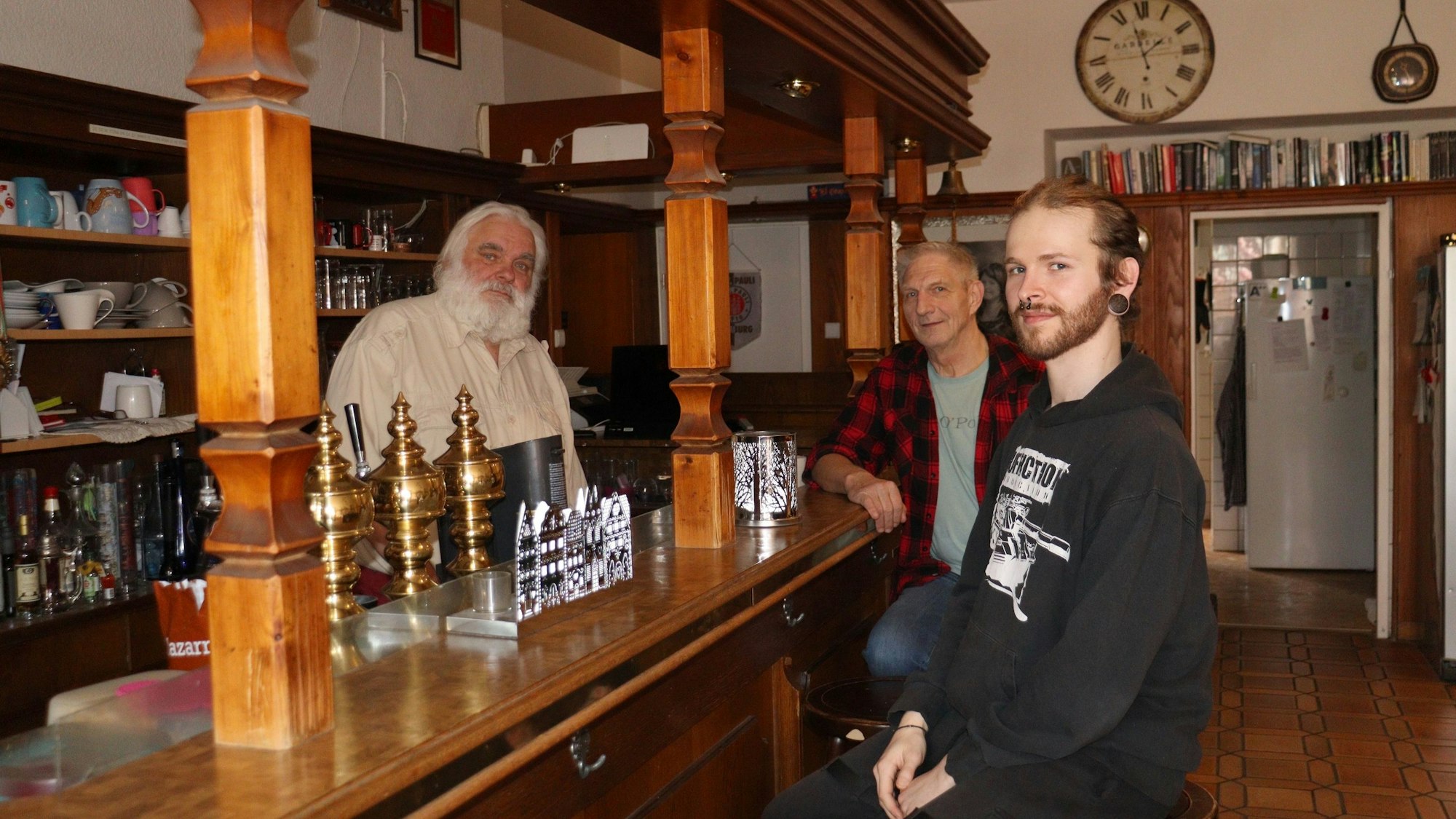 Drei Männer sitzen an einer Theke in dem ehemaligen Hotel.