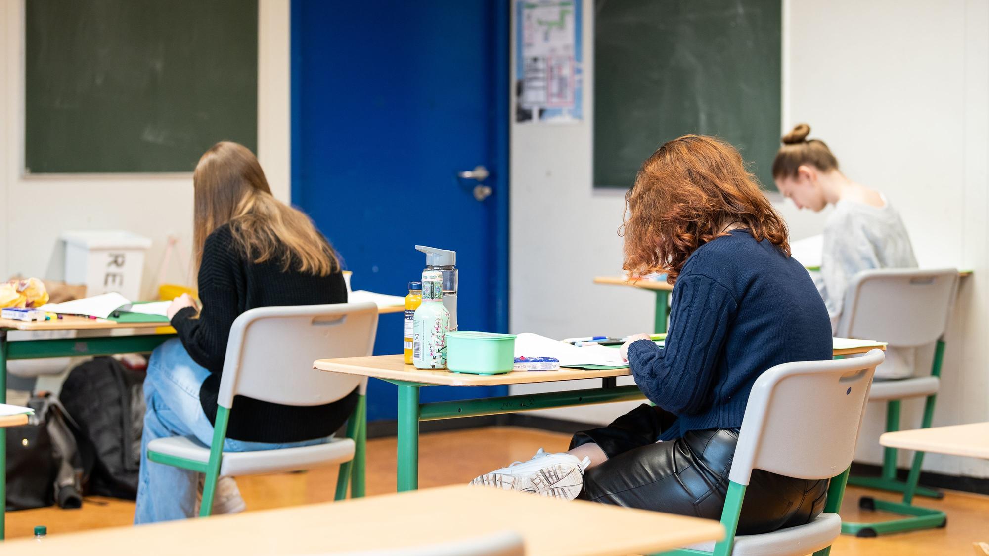 Schülerinnen und Schüler sitzen während der schriftlichen Abiturprüfung in einem Klassenzimmer.