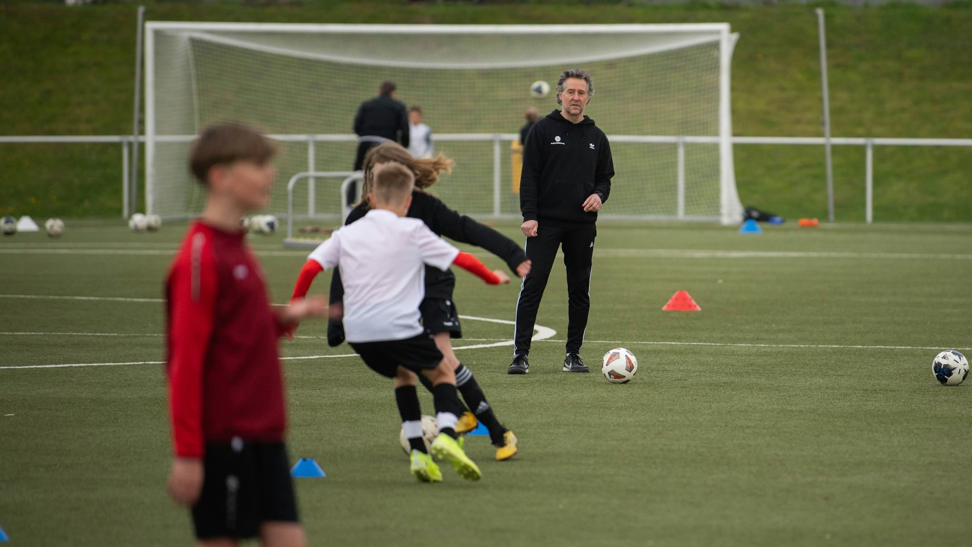 Trainingseinblick auf dem Kunstrasenplatz. Drei junge Talente trainieren am Ball.