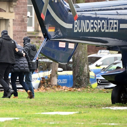 07.12.2022, Baden-Württemberg, Karlsruhe: Eine Person (2.v.r.) wird von Polizisten aus einem Hubschrauber gebracht.