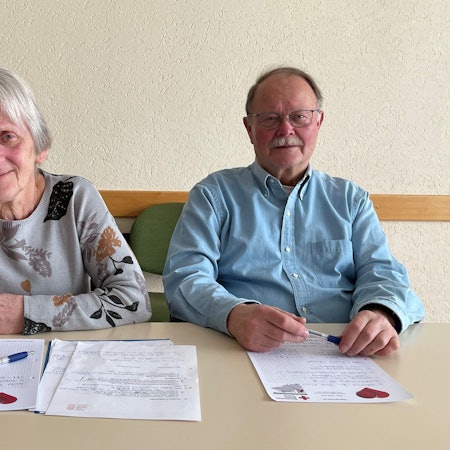 Dr. Renate Dietz und Peter Dreger sitzen an einem Tisch und haben auf diesem beschriftete Unterlagen vor sich liegen.