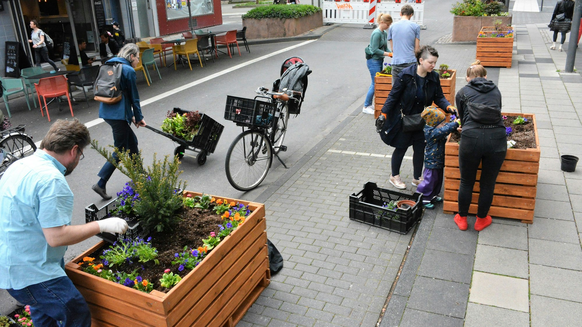 Deutzerinnen und Deutzer bepflanzen drei Beetkisten auf Parkplätzen und dem Bürgersteig auf der Deutzer Freiheit.