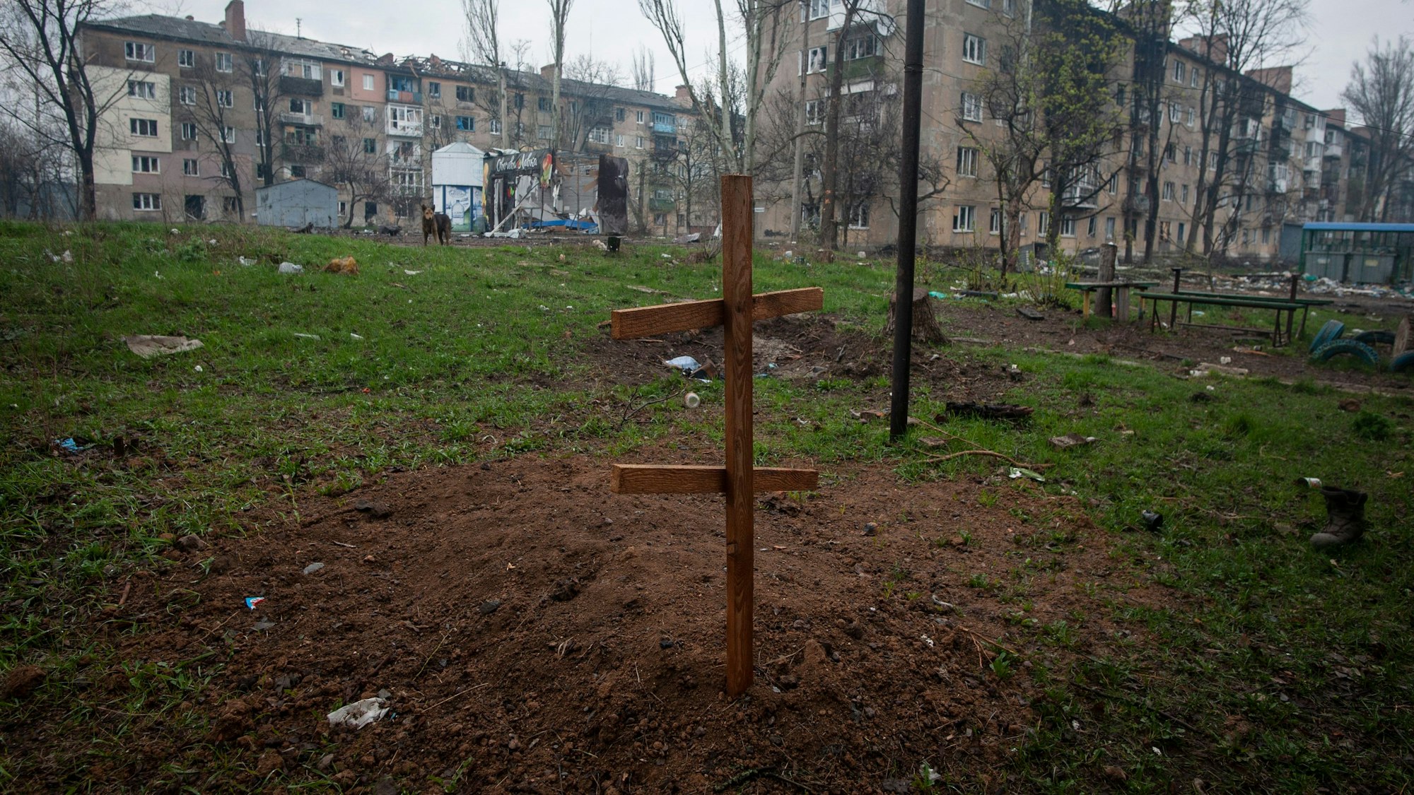 Ukraine, Bachmut: Ein Kreuz auf dem Grab eines Anwohners, der durch Beschuss getötet wurde, im Hof eines Wohnhauses.
