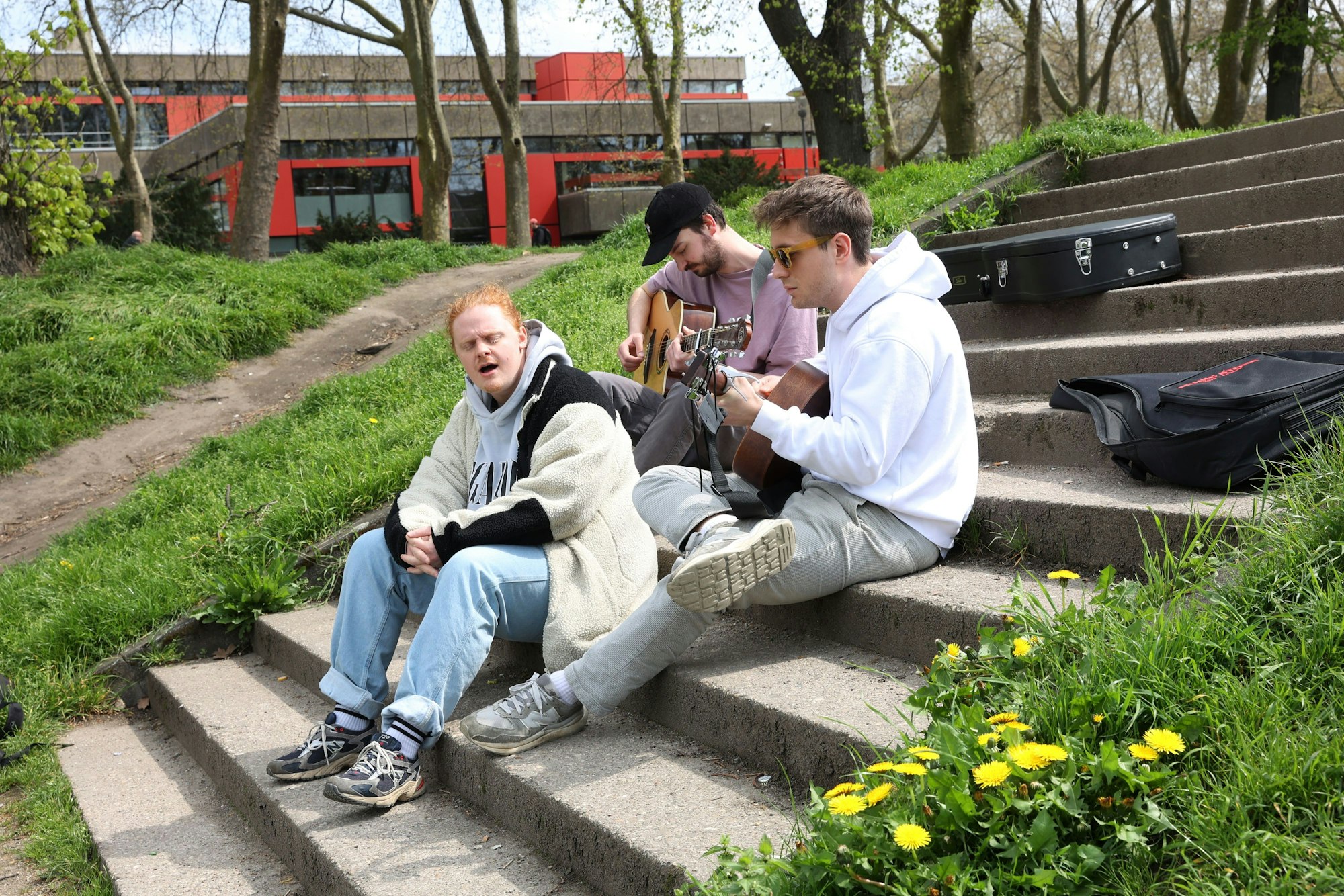 Jerome, Maurice und Kris sitzen auf einer Treppe und machen Musik.