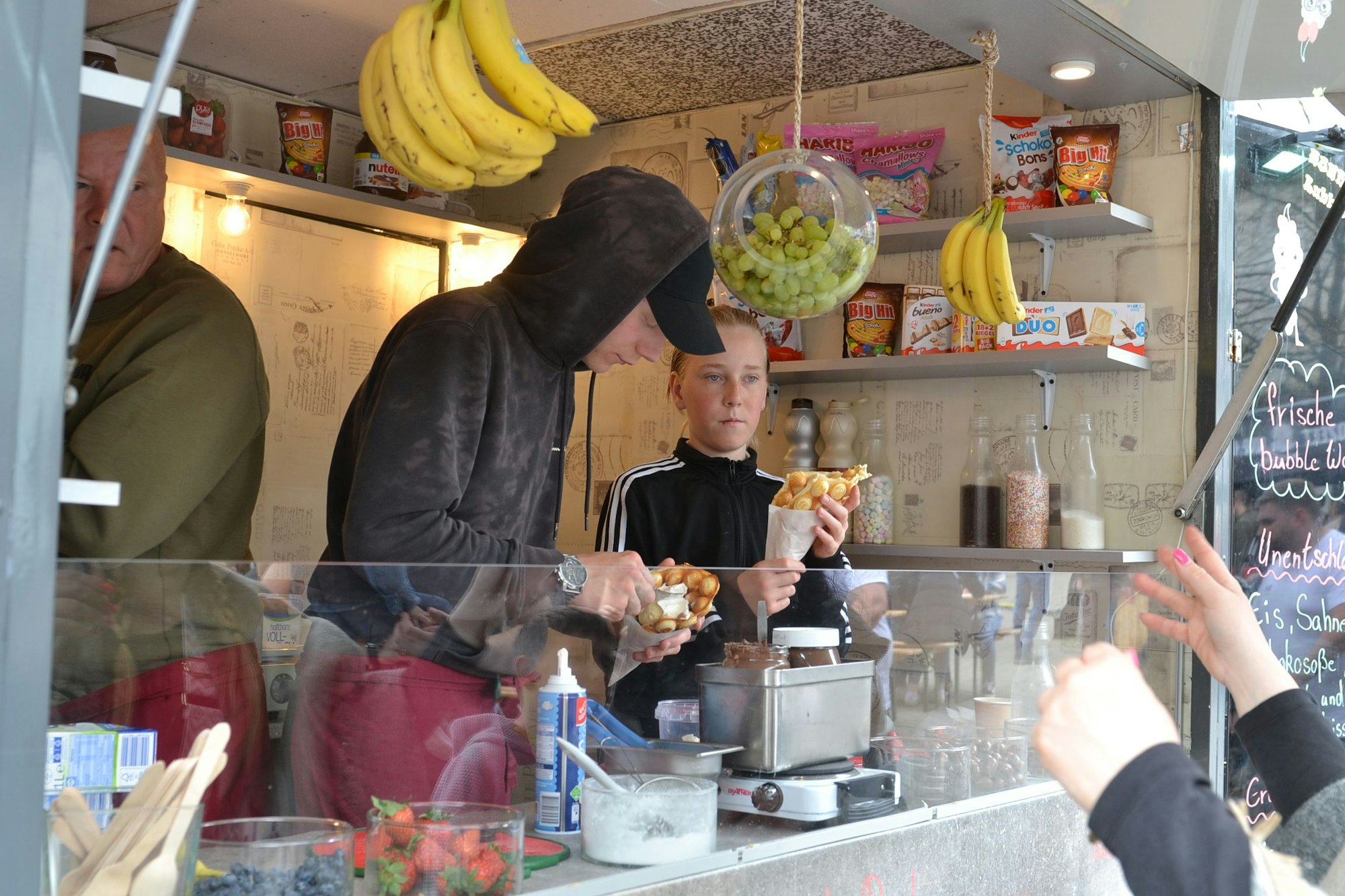 Das Team eines Foodtrucks reicht ihre Spezialitäten nach draußen.