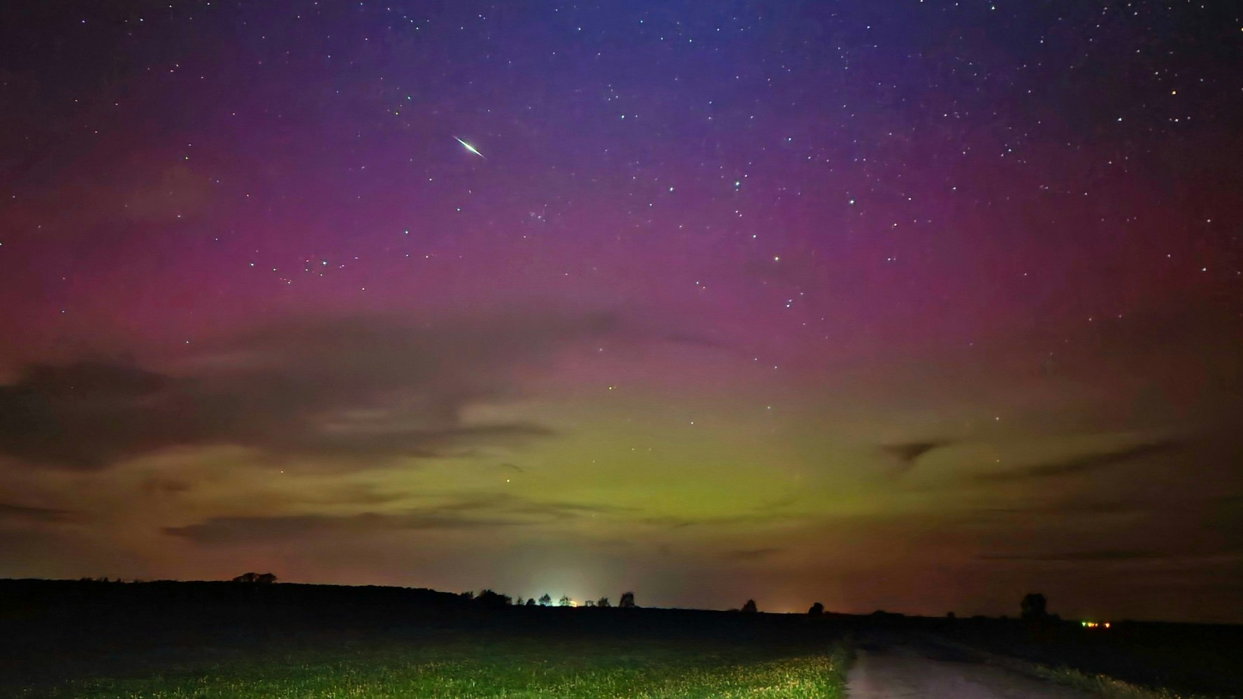 Ein Himmelskörper zieht durch die Polarlichter am nächtlichen Himmel. Das Bild wurde in Fischbeck, Sachsen-Anhalt aufgenommen.