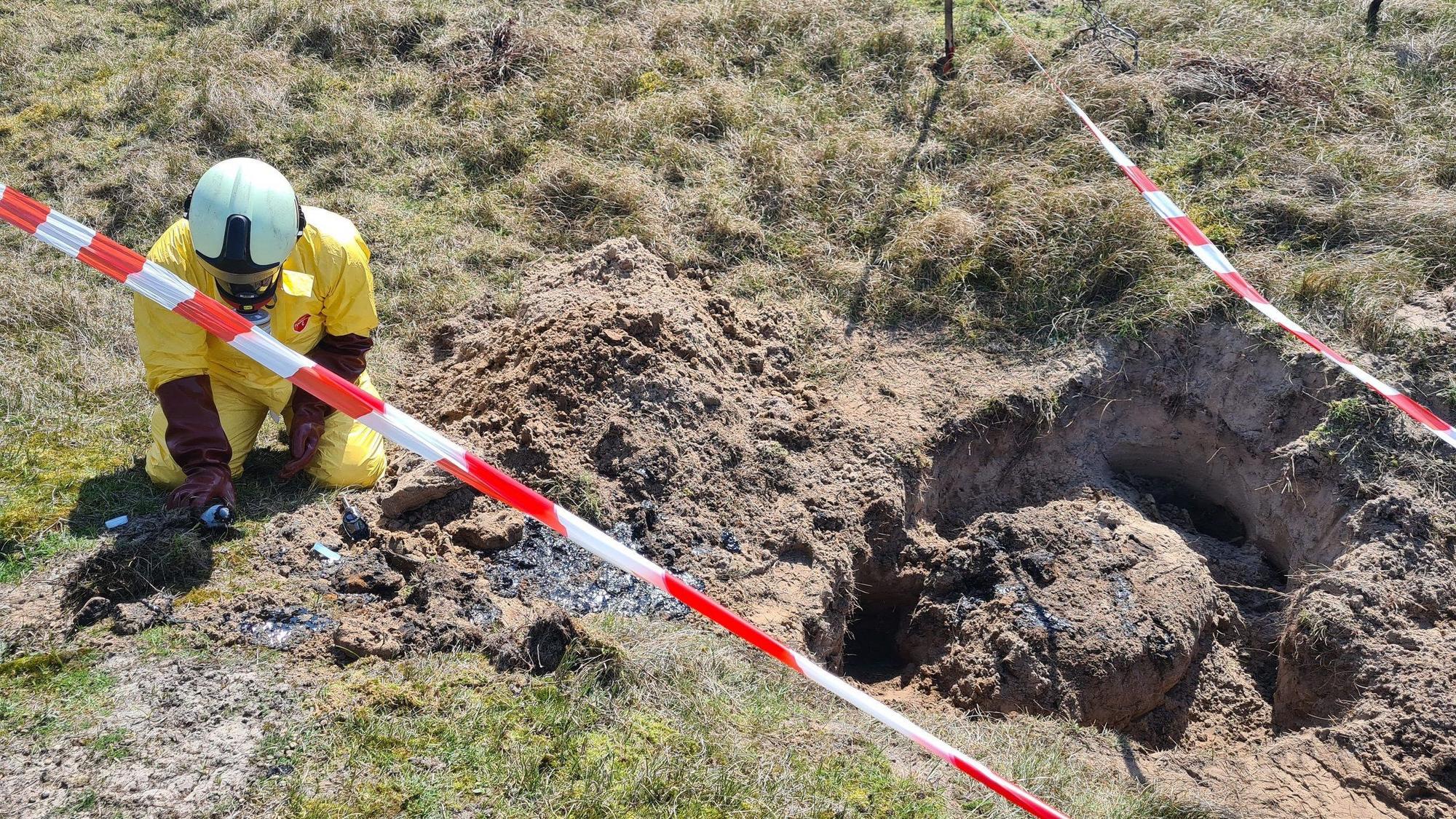 Ein Gefahrgutspezialist der Feuerwehr untersucht in den Dünen im Osten der ostfriesischen Insel Baltrum eine unbekannte, dunkele Substanz. Der Ort ist mit rot-weißem-Flatterband abgesperrt.