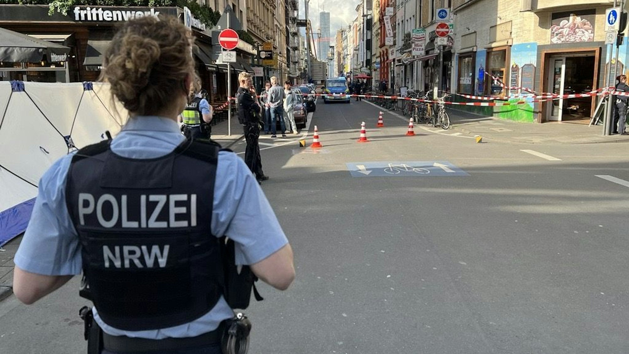 Eine Polizistin schaut auf den Tatort der Schlägerei auf dem Friesenwall.