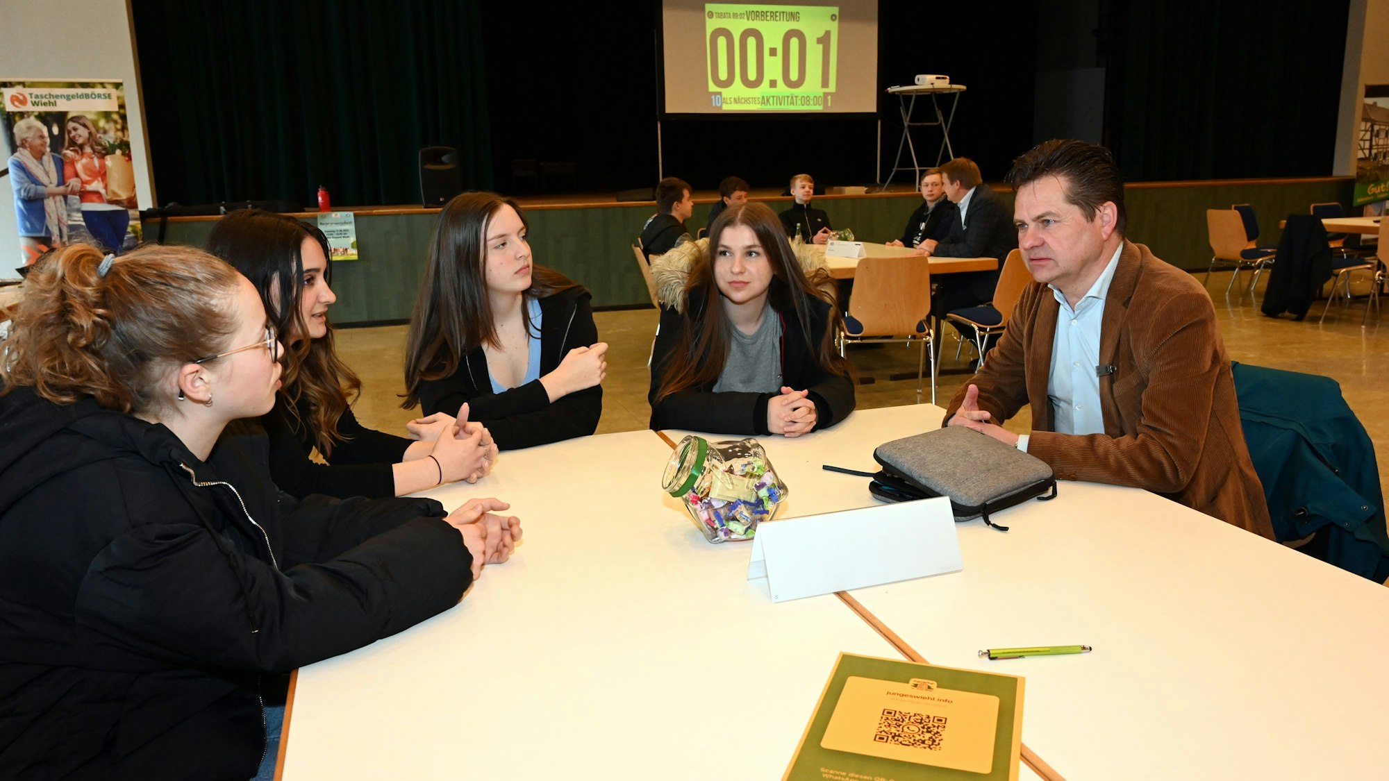 Bürgermeister Ulrich Stücker sitzt an einem Tisch mit vier Neuntklässlerinnen.