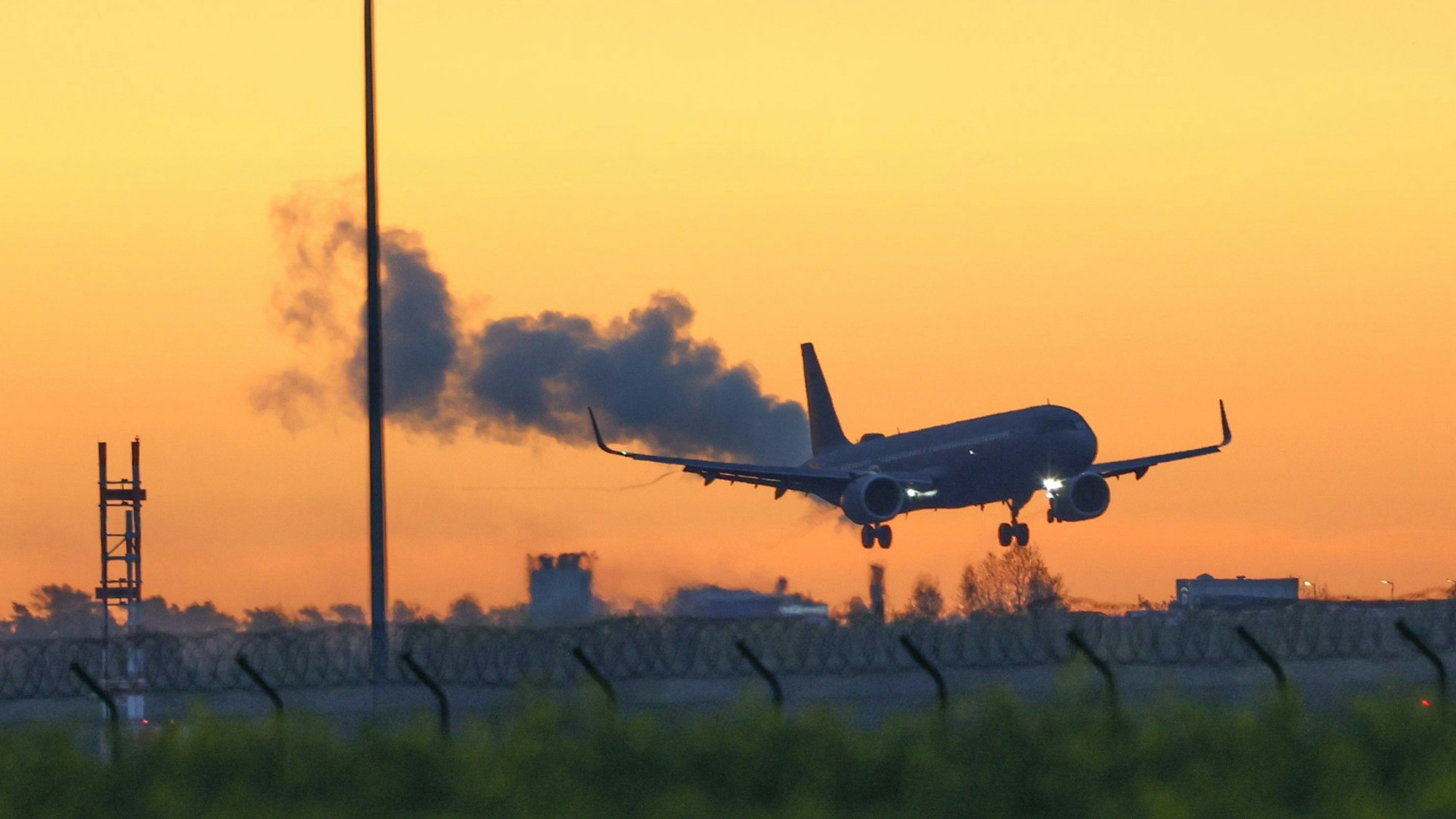 Ein Airbus der Luftwaffe fliegt vor einem goldenen Morgenhimmel den Flughafen BER in Berlin an.