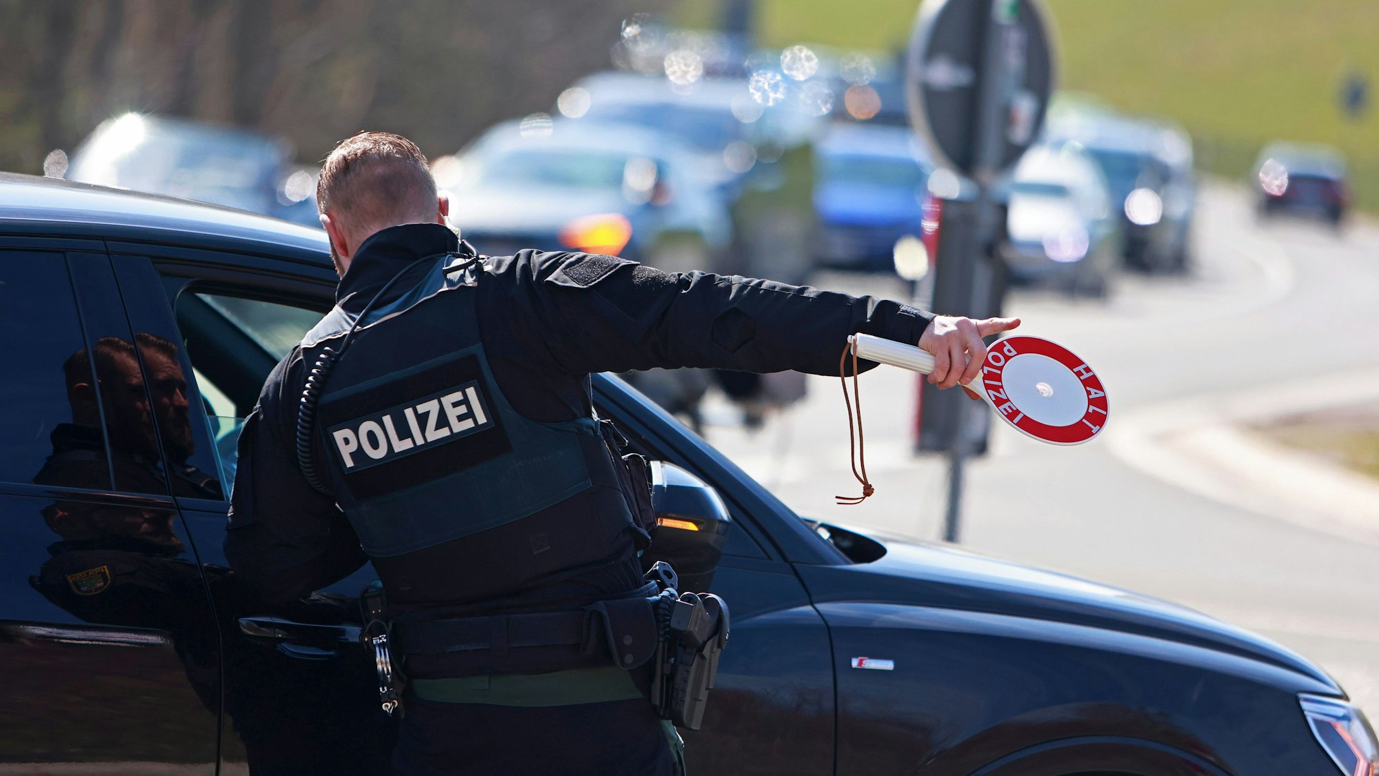 Einsatzkräfte der Polizei kontrollieren Verkehrsteilnehmer. Ein Polizist steht vor einem Auto und spricht von der Beifahrerseite aus mit einem Fahrer.
