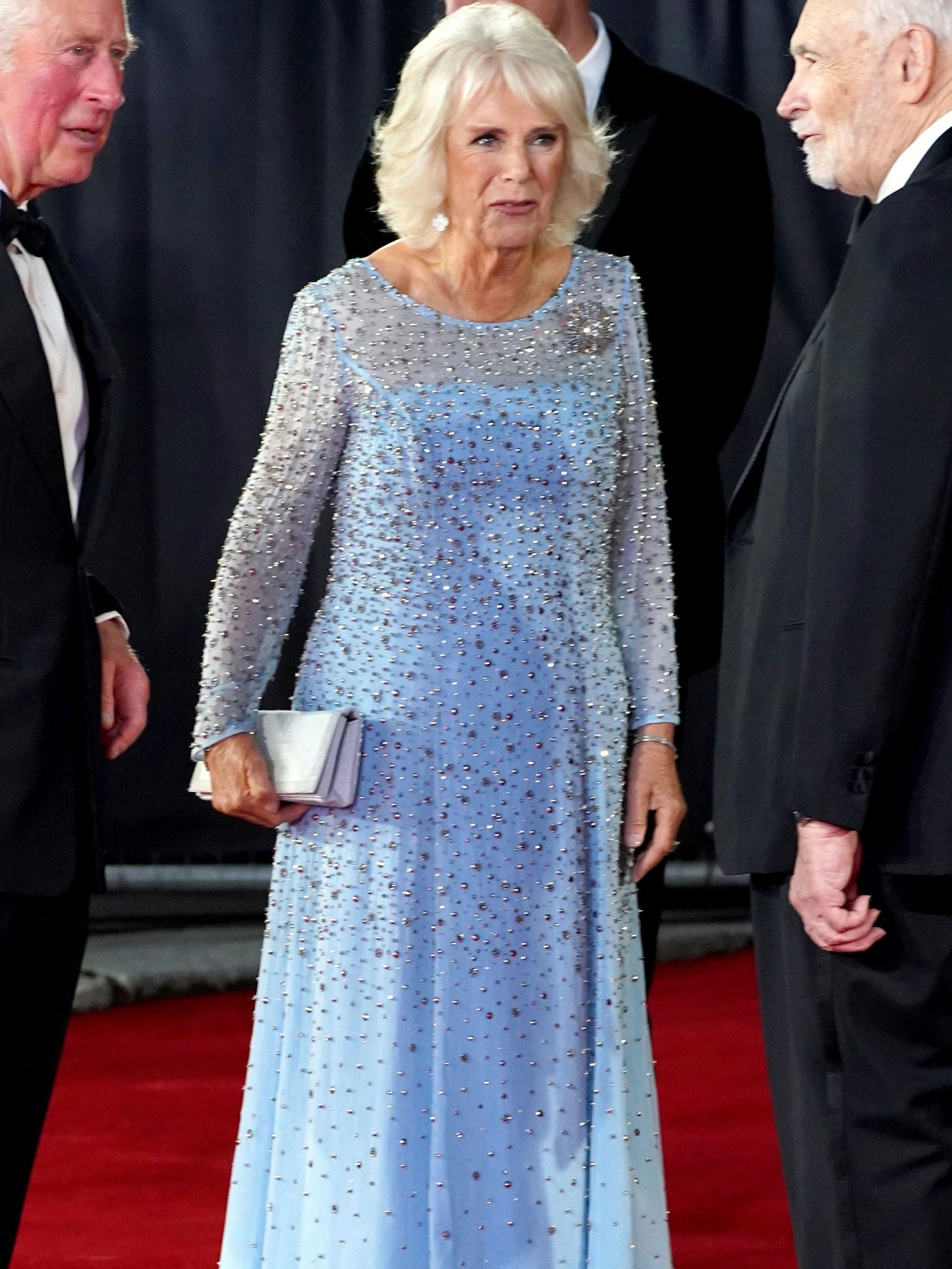 Der britische Prinz Charles (l), Prinz von Wales, und seine Ehefrau Camilla (m), Herzogin von Cornwall, bei der Weltpremiere des James Bond Films „No Time to Die“ in der Royal Albert Hall.