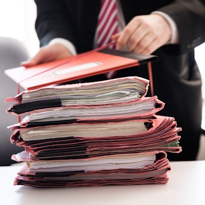 Ein Oberstaatsanwalt bindet einen Stapel Gerichtsakten auf seinem Schreibtisch in den neuen Räumen der Generalstaatsanwaltschaft Hamburg zusammen.