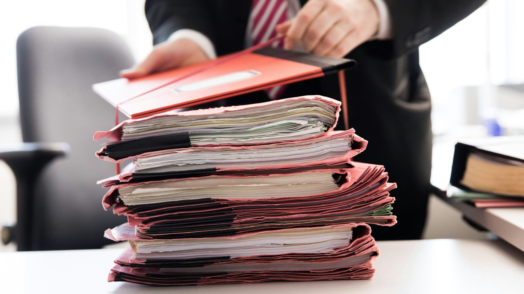 Ein Staatsanwalt bindet einen Stapel Gerichtsakten auf seinem Schreibtisch.