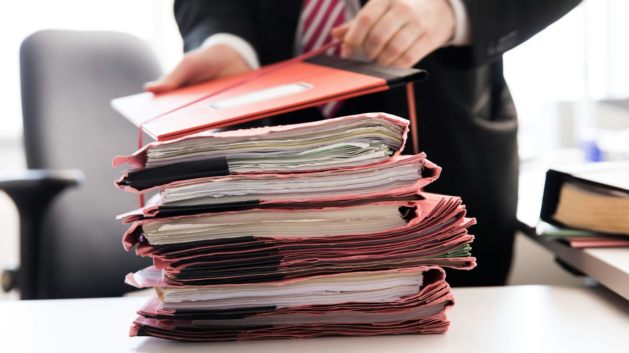 Ein Oberstaatsanwalt bindet einen Stapel Gerichtsakten auf seinem Schreibtisch in den neuen Räumen der Generalstaatsanwaltschaft Hamburg zusammen.