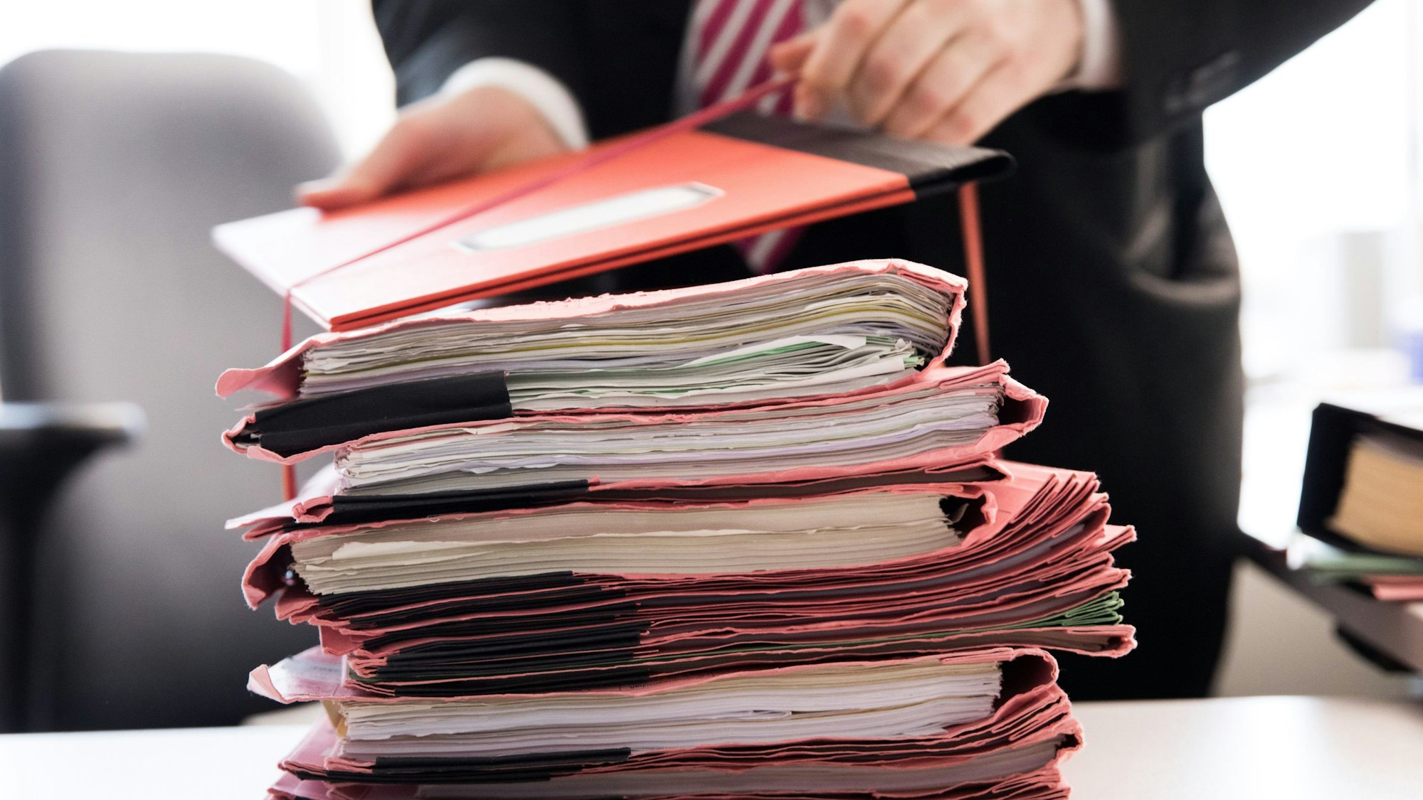 Ein Oberstaatsanwalt bindet einen Stapel Gerichtsakten auf seinem Schreibtisch.