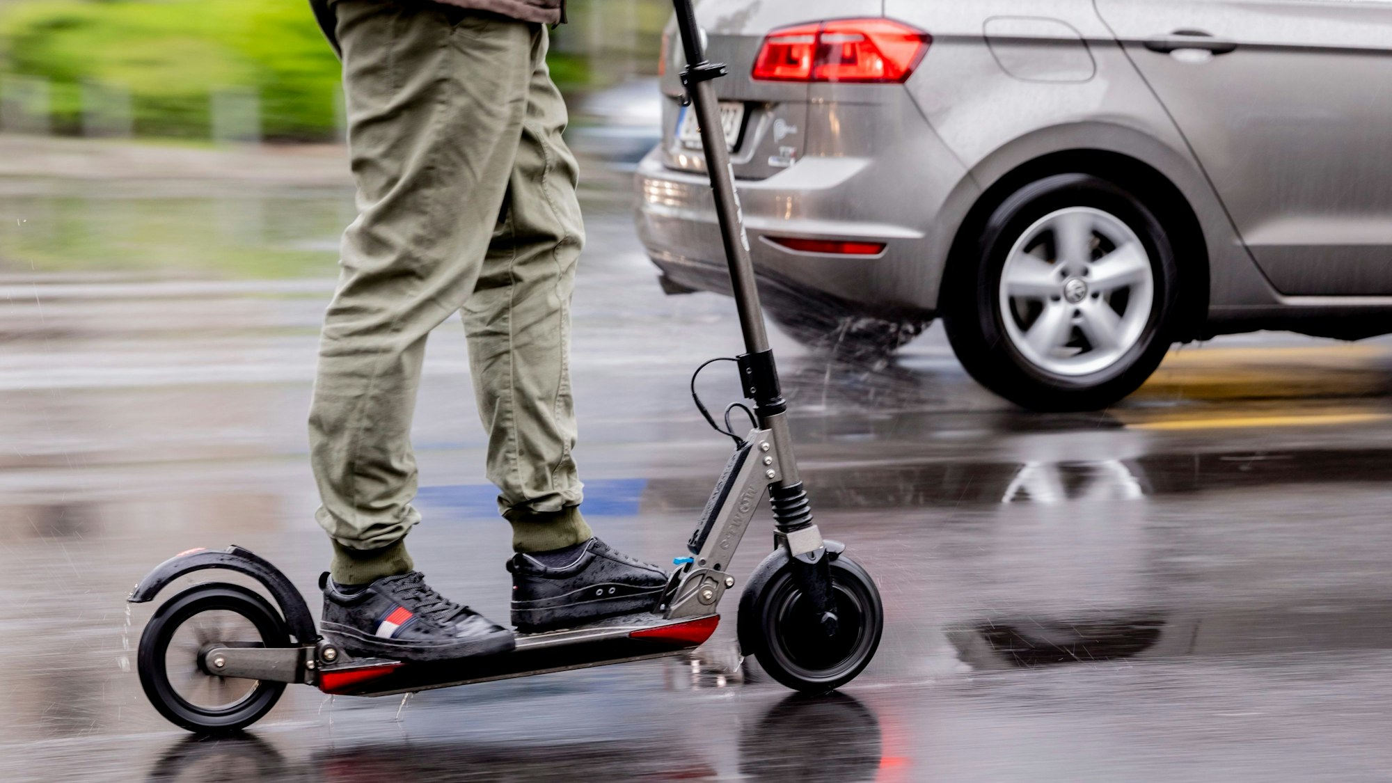 Ein Mann fährt mit einem E-Scooter auf der Straße.