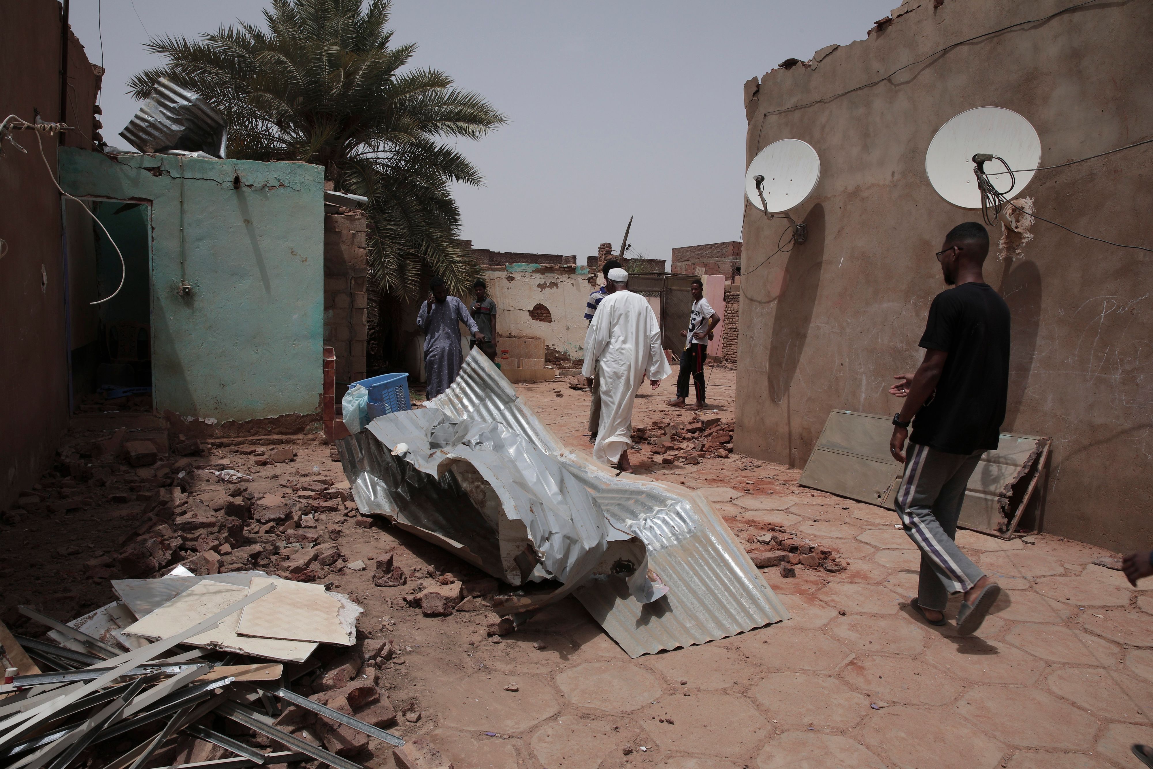 25.04.2023, Sudan, Khartum: Menschen gehen an einem Haus vorbei, das bei den jüngsten Kämpfen beschädigt wurde.