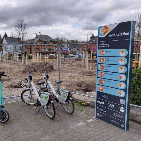 Zwei Leihräder und ein Roller stehen an der eingezäunten Mobilstation neben der Baustelle am Stadtpark Leichlingen