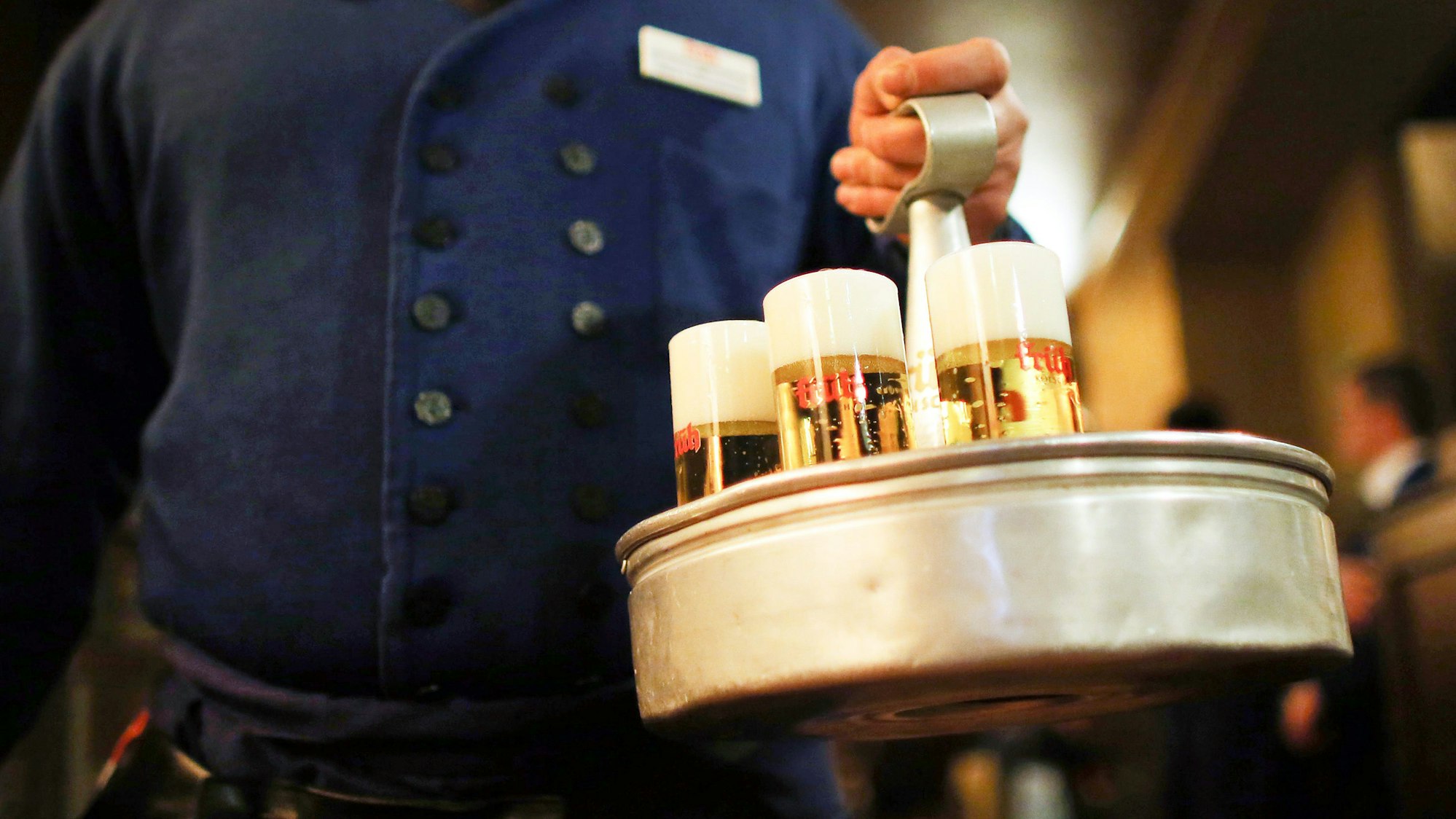 Ein Köbes (Kellner) trägt im Brauhaus Früh am Dom Kölsch-Bier.