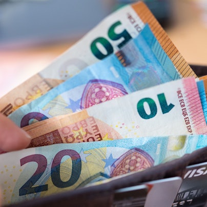 Eine Frau hält eine Geldbörse mit Banknoten in der Hand