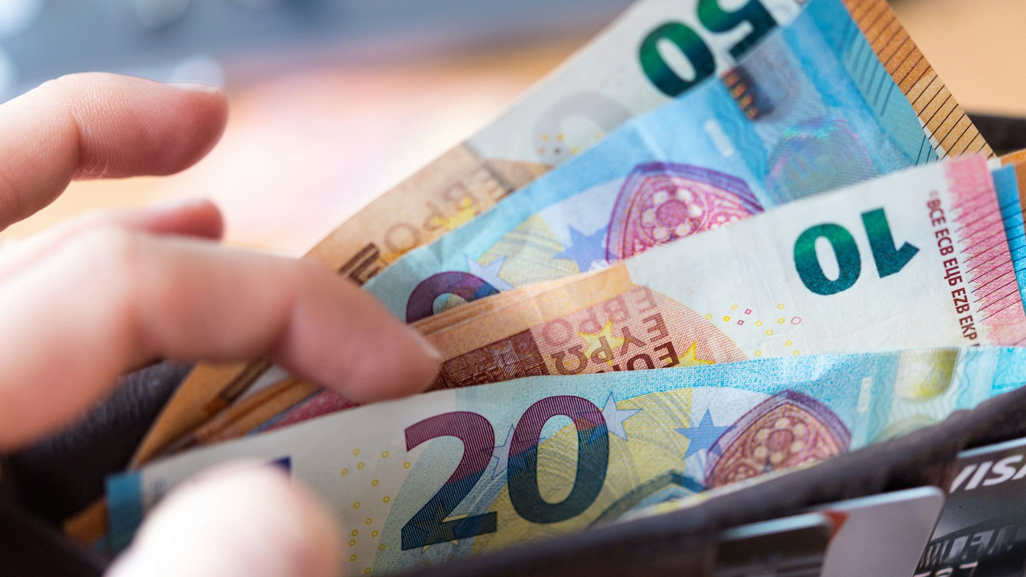 Eine Frau hält eine Geldbörse mit Banknoten in der Hand