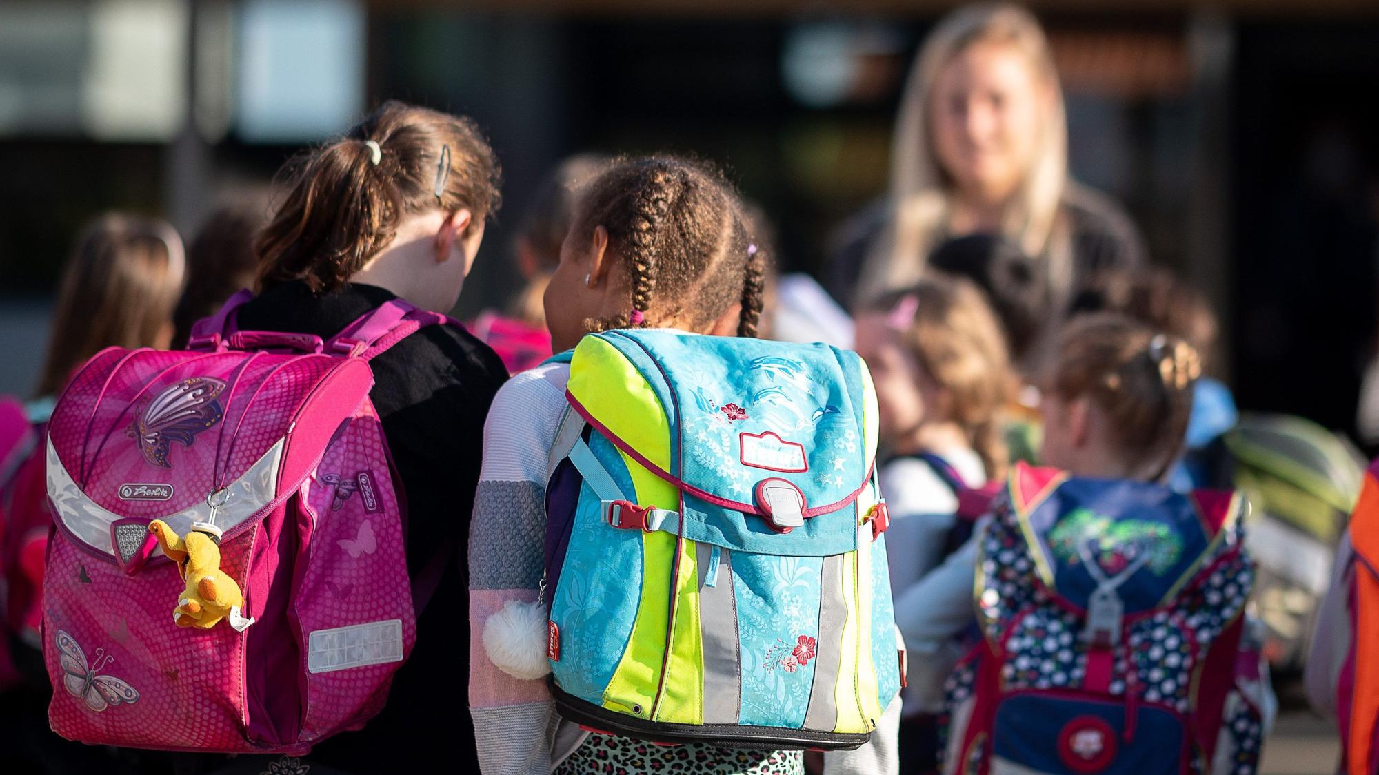 Grundschulkinder von hinten mit ihren Ranzen.