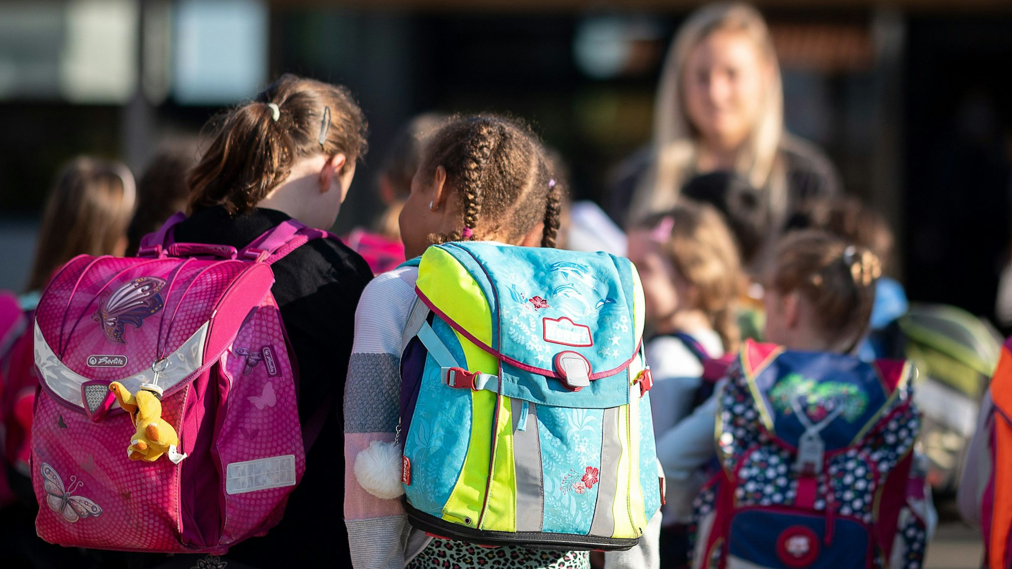 Grundschulkinder von hinten mit ihren Ranzen.